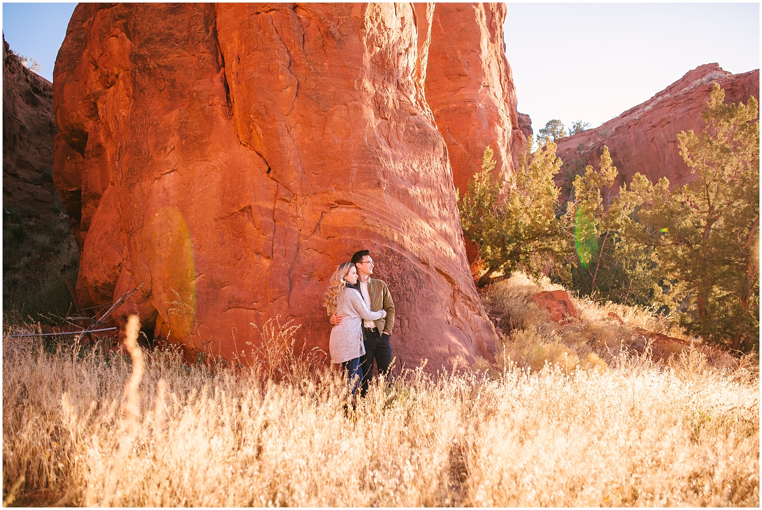 Couple hugging in a field by red rocks in Jemez New Mexico