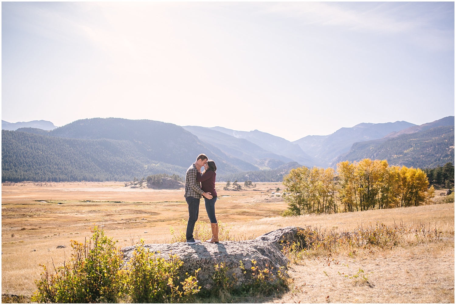 Couple kissing on rock in Moraine Valley at Rocky Mountain National Park fall engagement
