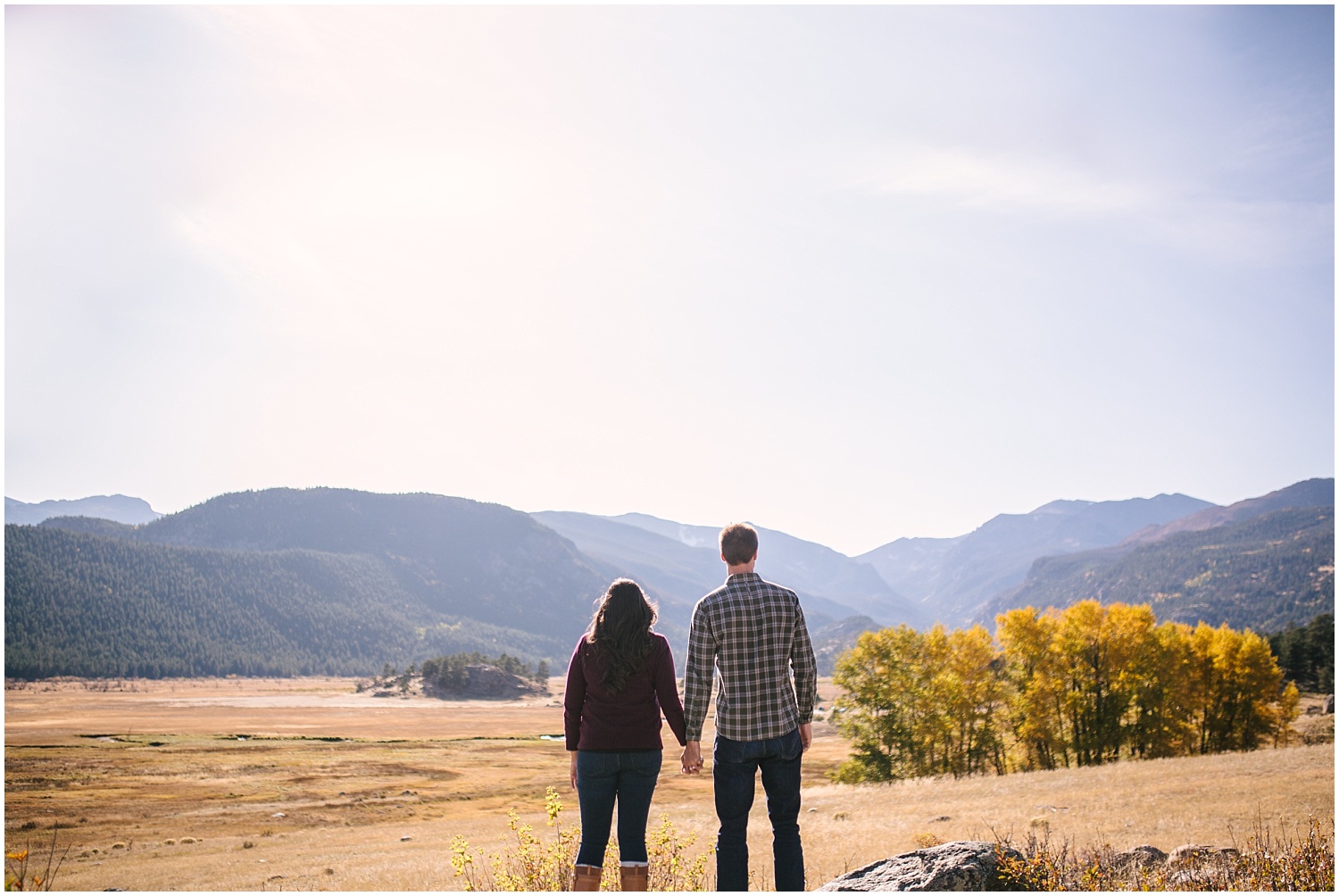 Couple standing on rock overlooking mountains in Moraine Valley at Rocky Mountain National Park for fall engagement
