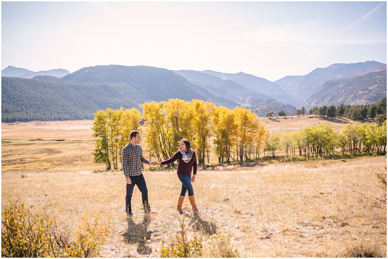 Couple walking in field with yellow aspens for fall engagement at Rocky Mountain National Park