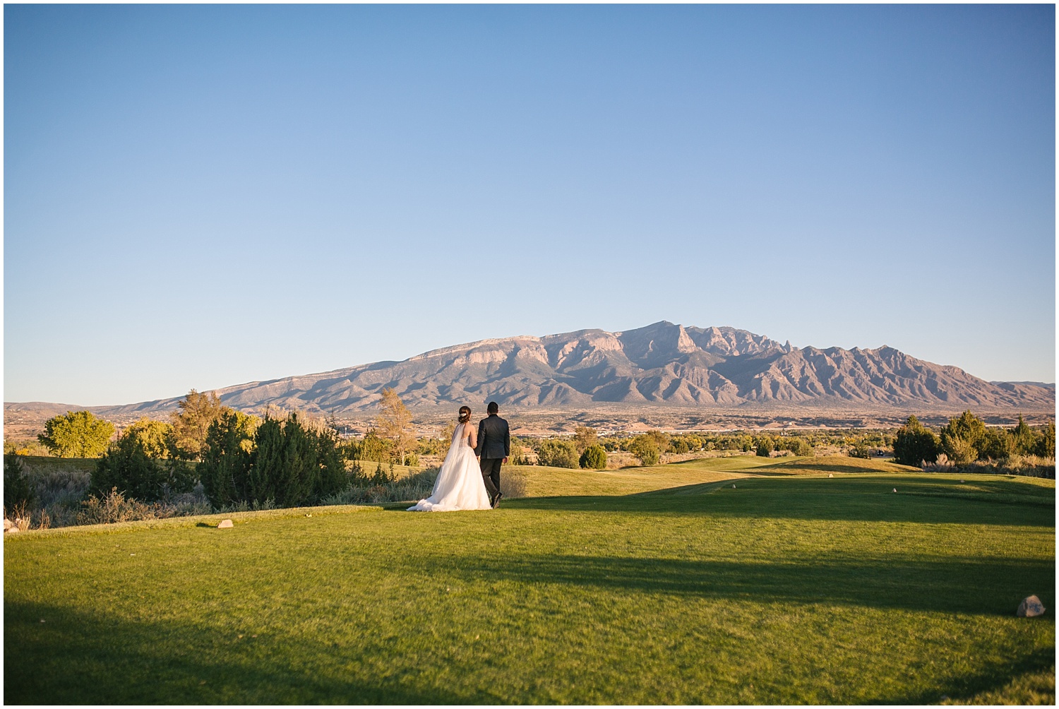 Bride and groom look at the giant Sandia Mountains from the Santa Ana Golf Course at Prairie Star Restaurant wedding