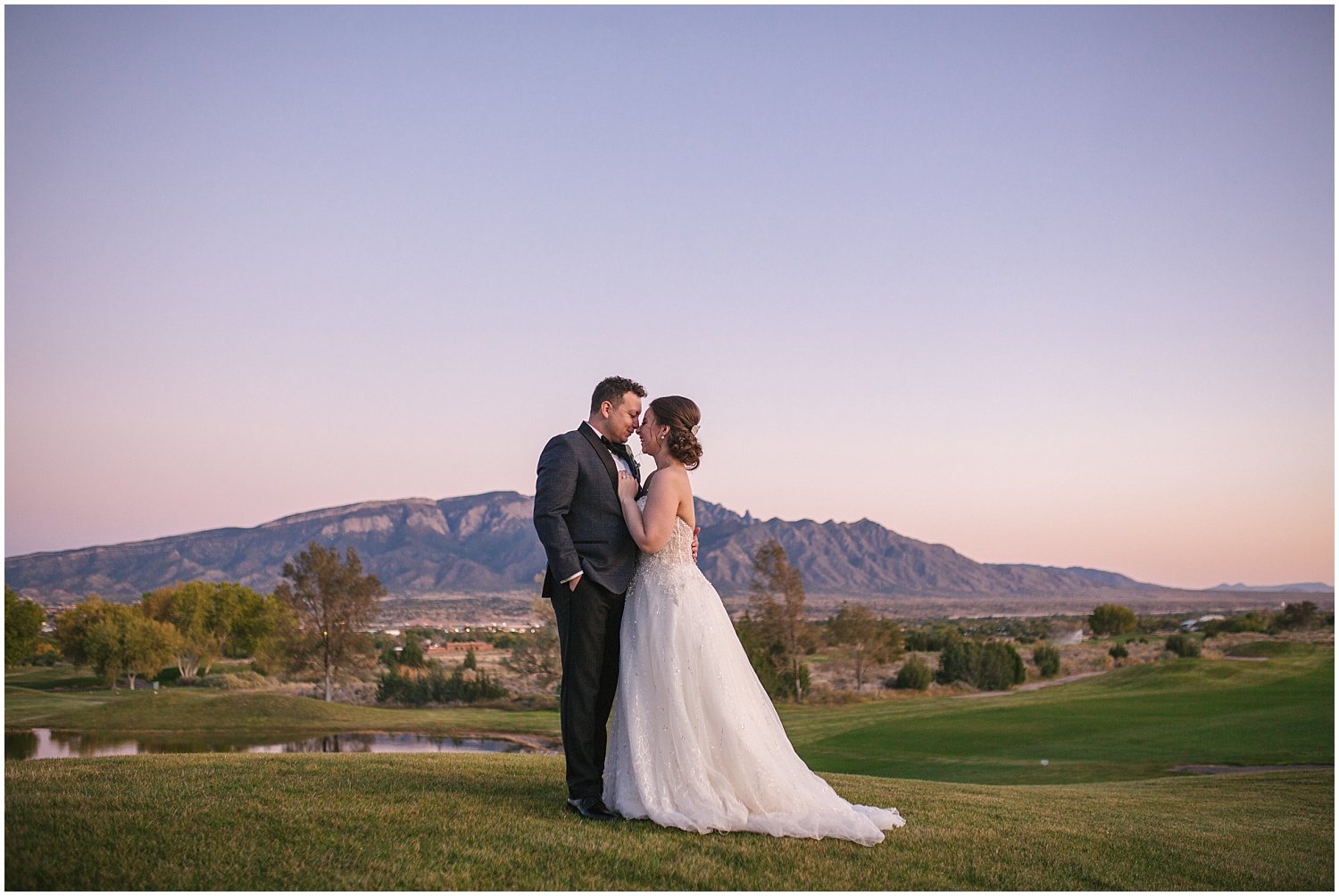 Bride and groom hugging in front of Sandia Mountains at sunset for fall wedding at Prairie Star Restaurant