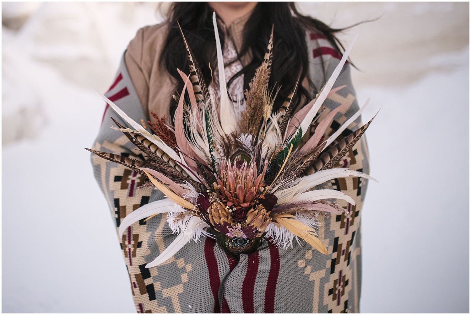 Bride holds boho bouquet and southwest style blanket for winter elopement at Paint Mines in Colorado