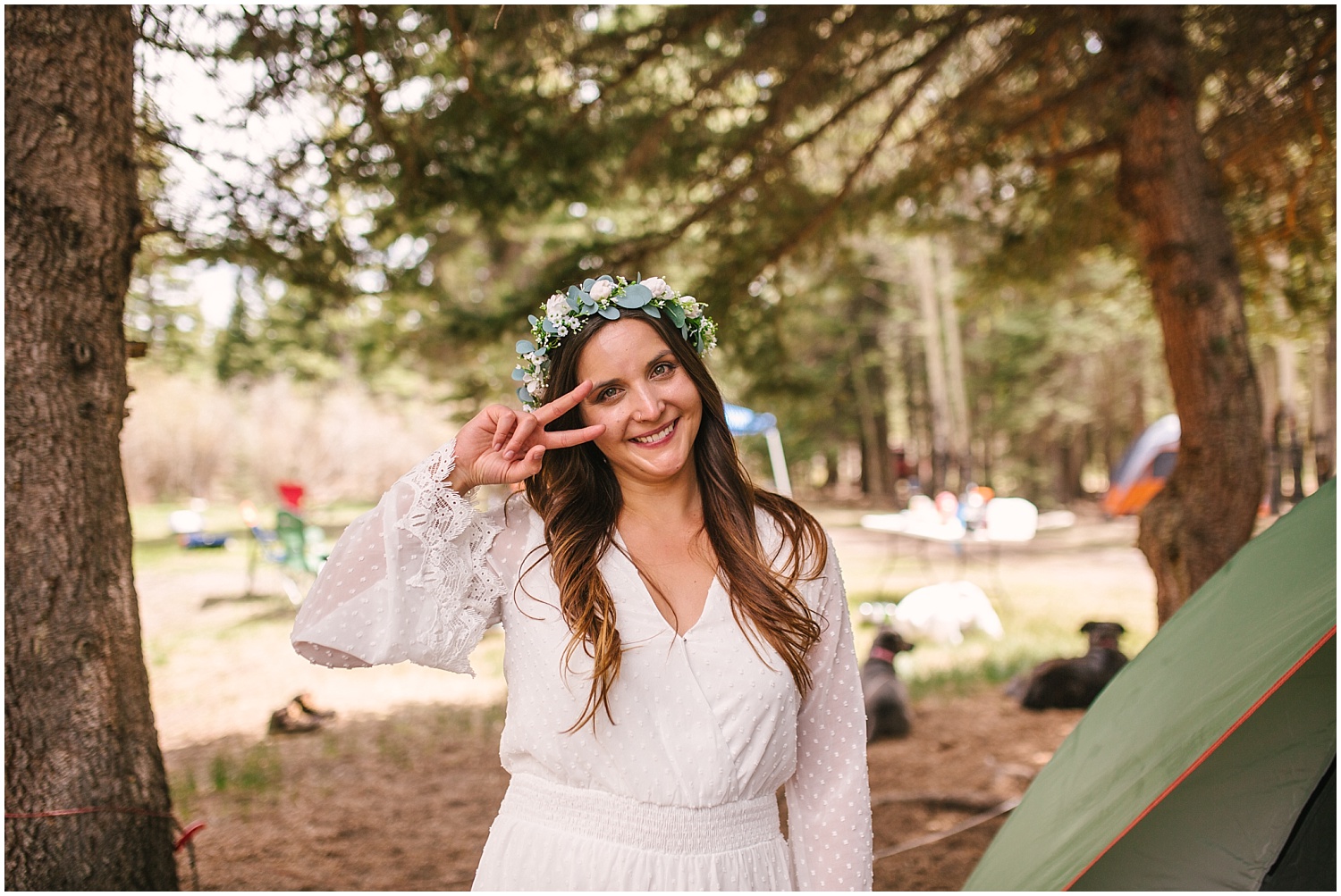 Bride in white romper and flower crown at campsite elopement