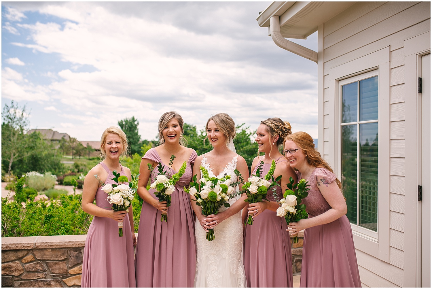 Bride with bridesmaids in floor-length pink dresses and white and green bouquets