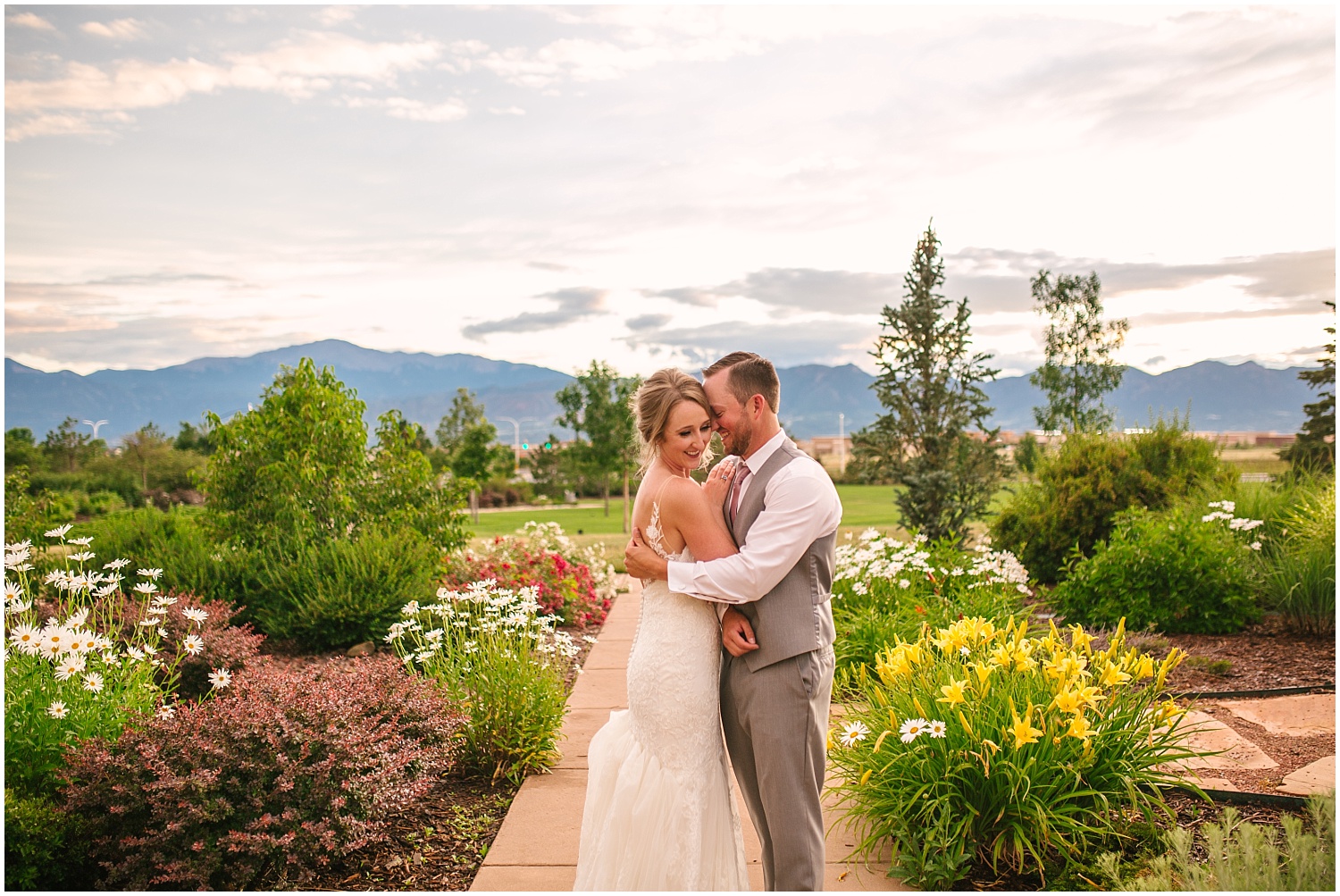 Bride and groom hugging surrounded by flowers and mountains in Colorado Springs