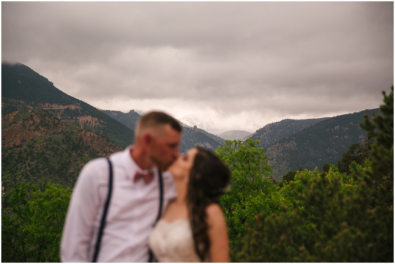 Thunderstorms over Pikes Peak behind kissing bride and groom