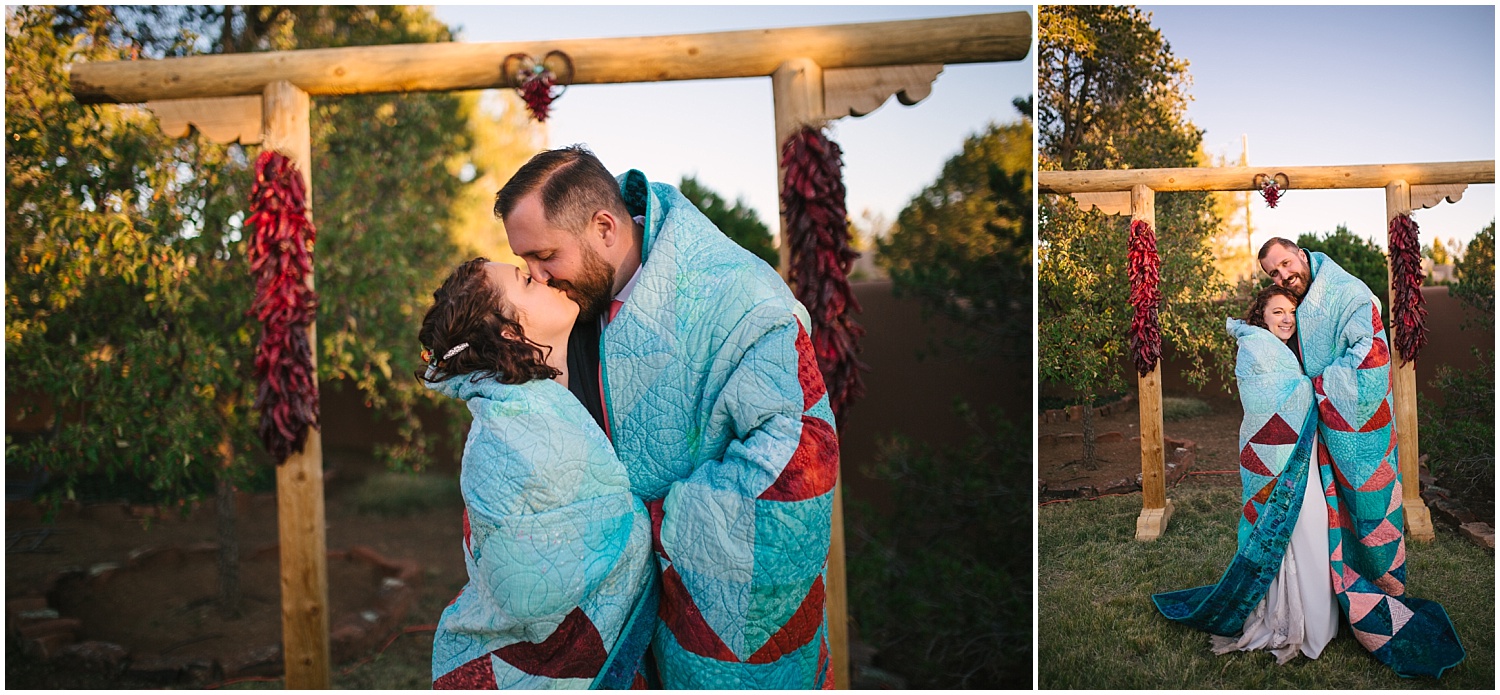bride and groom kissing under homemade quilt - a wedding gift from the bride's parents