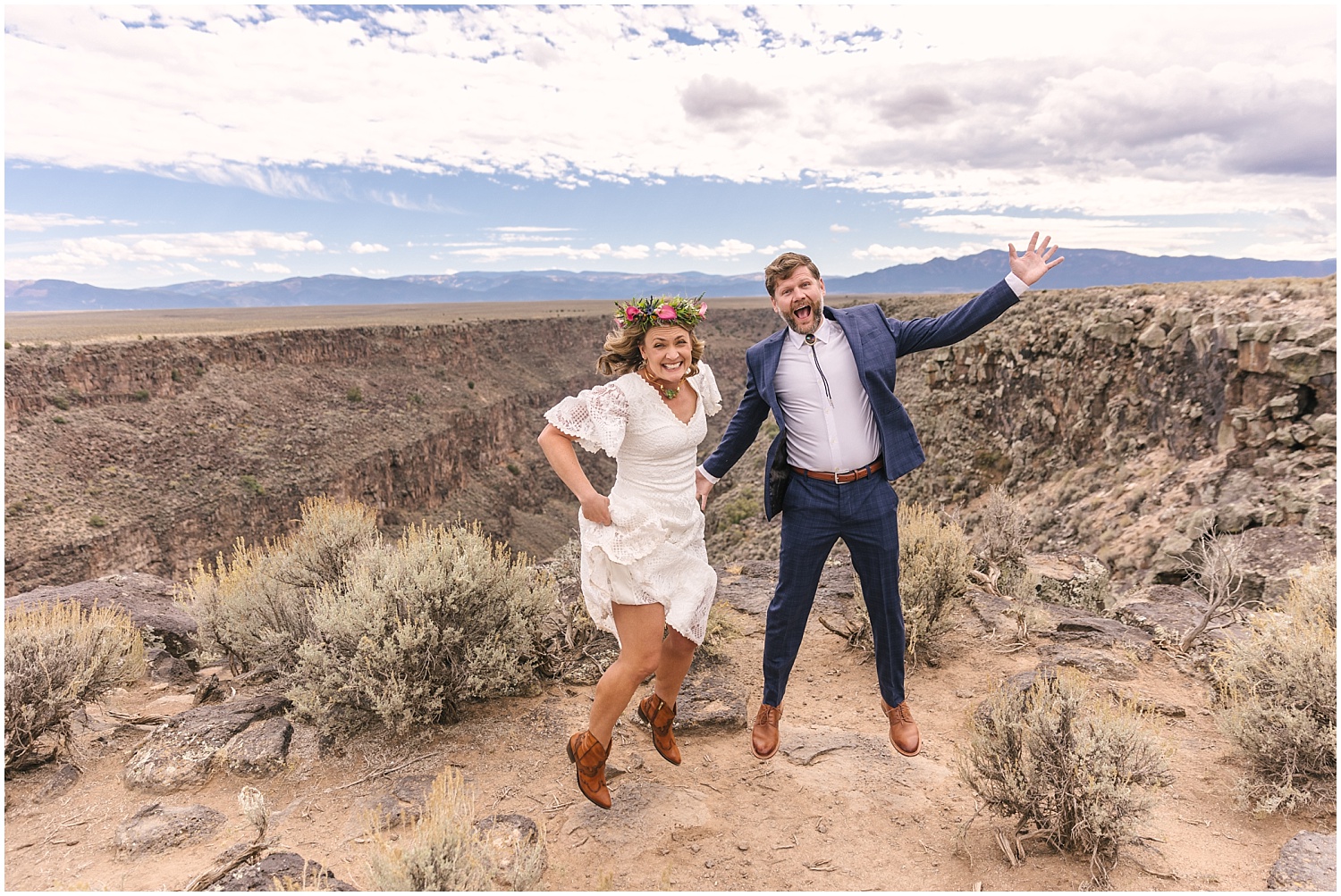 Bride and groom jumping for joy at the edge of the Rio Grande Gorge