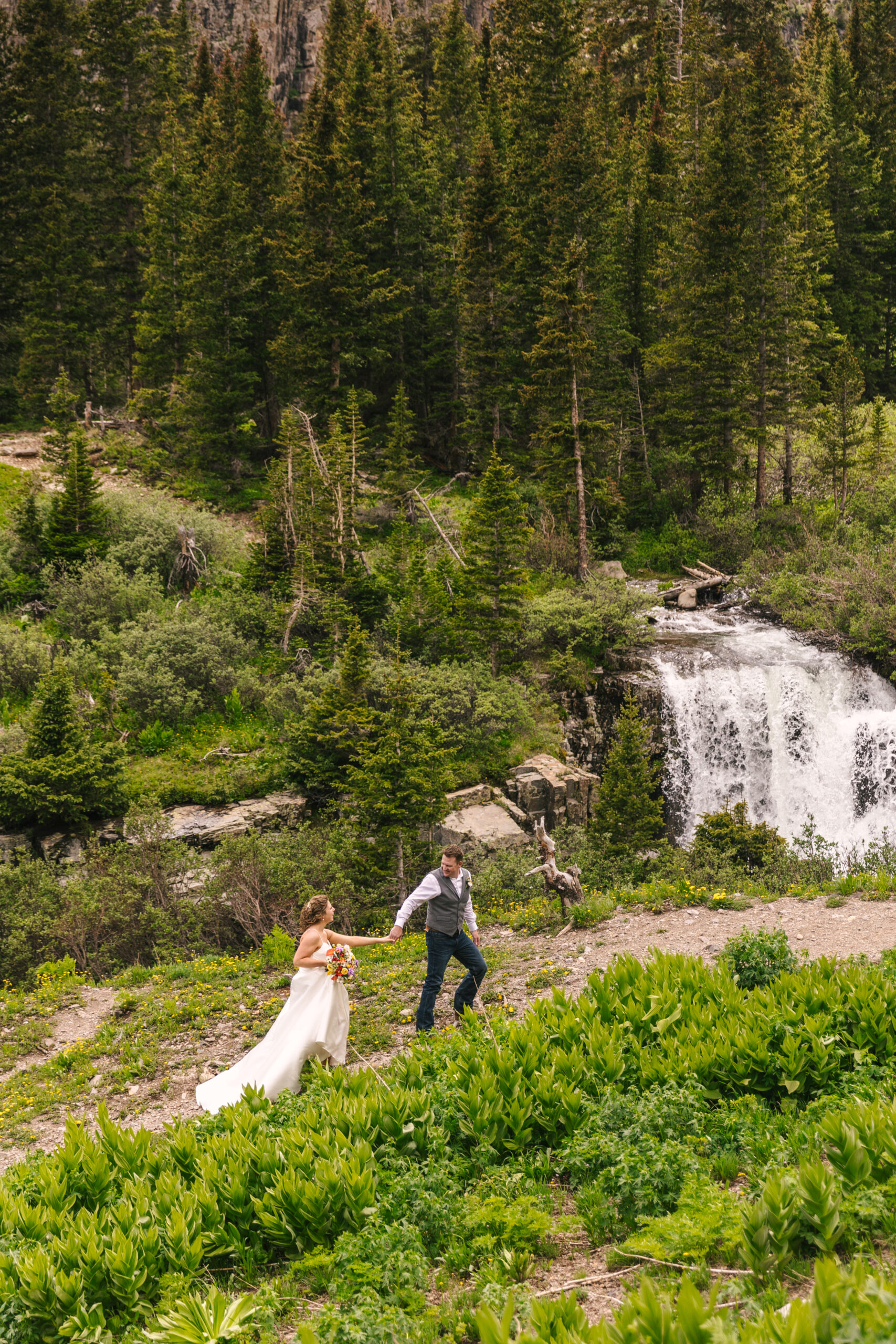 bride and groom walking near waterfall in summer elopement near Telluride Colorado