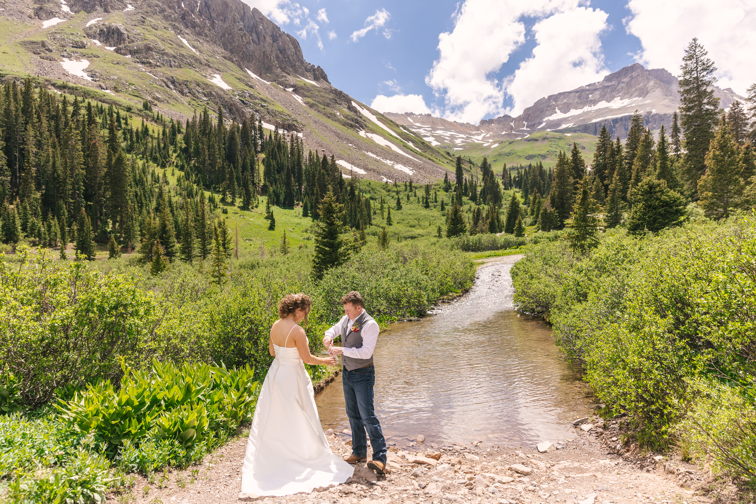 groom collecting water from stream in Colorado adventure elopement