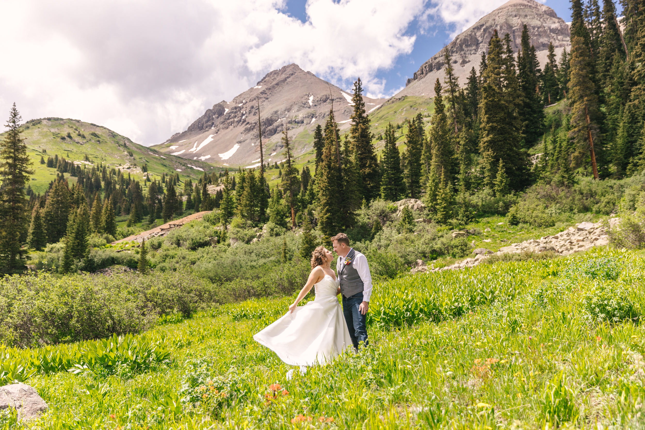 bride and groom portraits in green field of wildflowers for summer Colorado mountain elopement