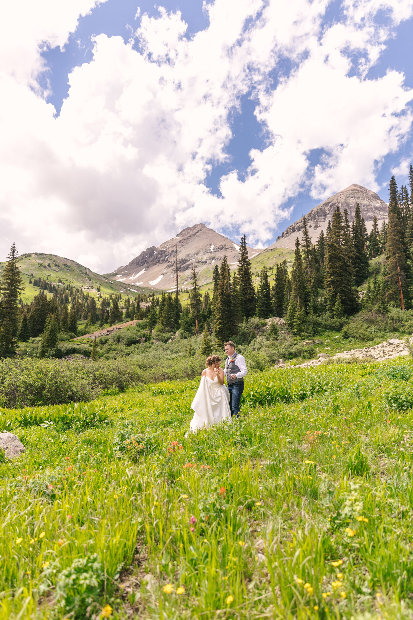 bride and groom dancing in green valley with wildflowers for summer Ouray Colorado adventure elopement