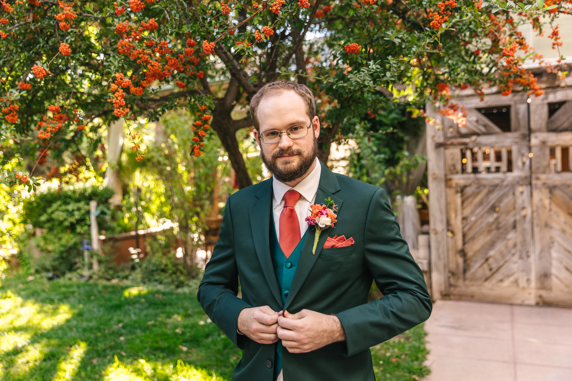 groom wearing emerald green suit and coral tie for September wedding
