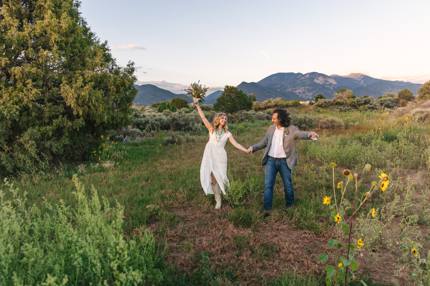 wedding couple walking in a green field outside Taos New Mexico