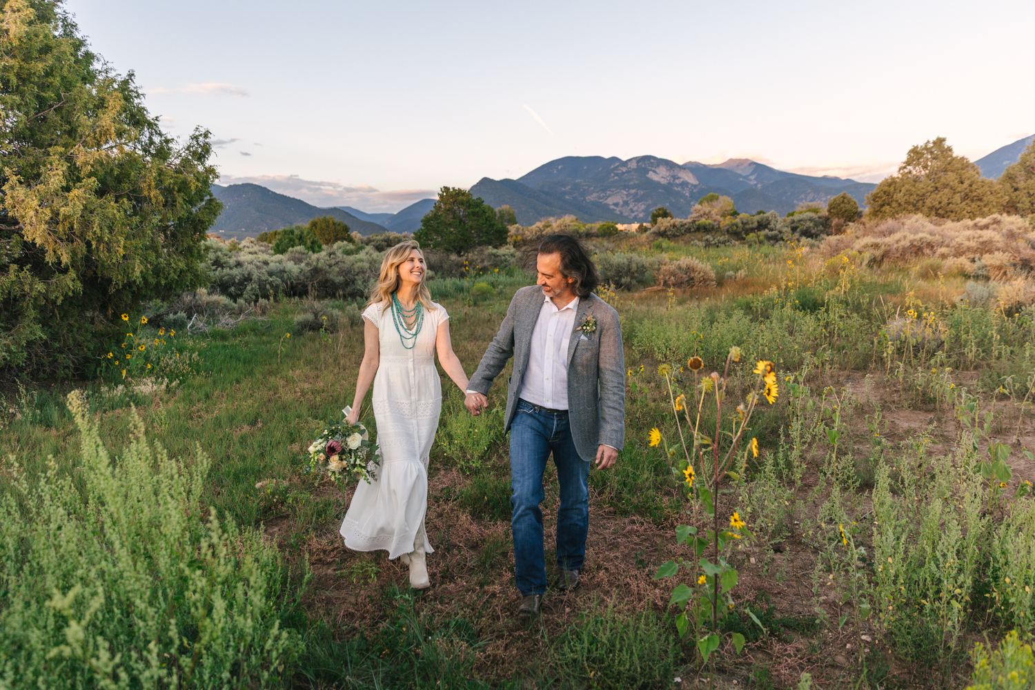 wedding couple walking in a green field outside Taos New Mexico