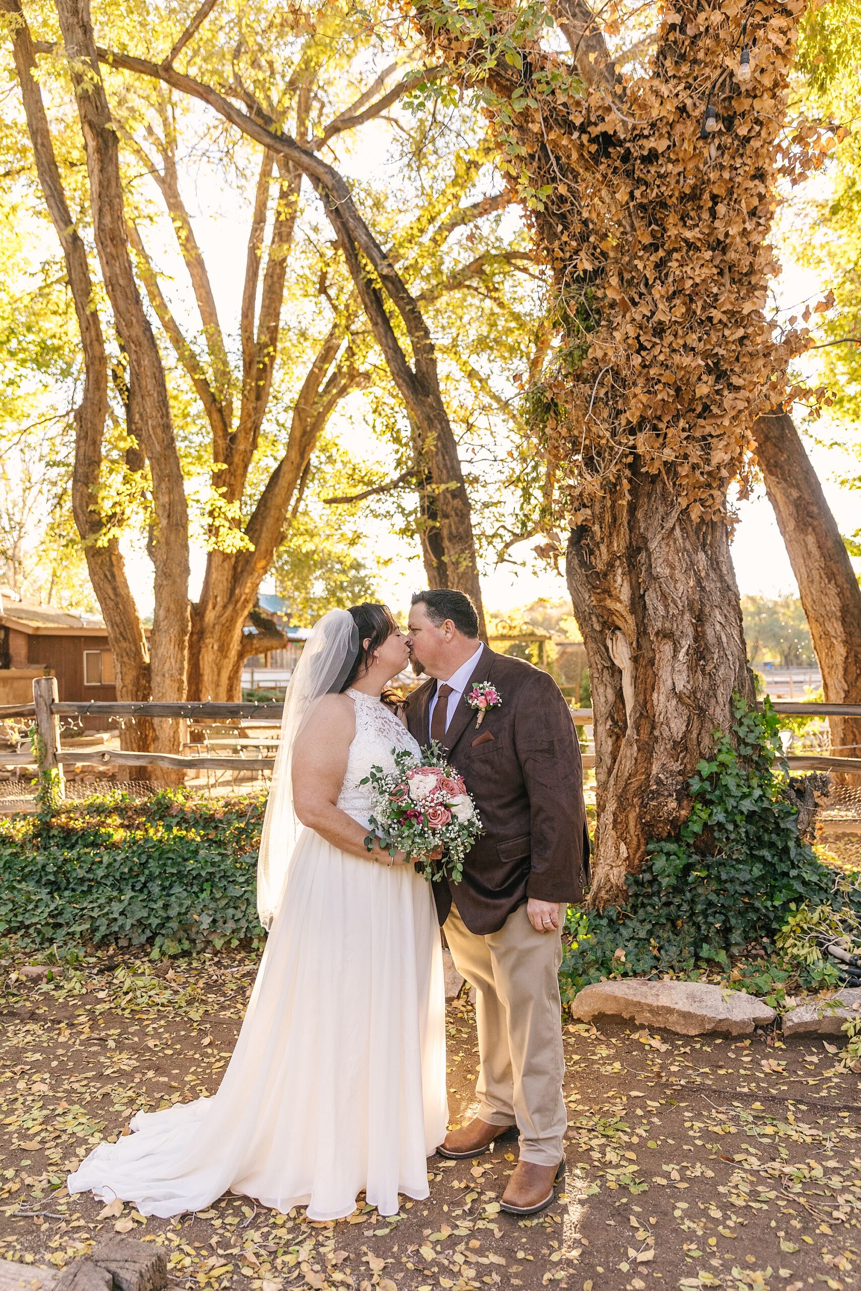 bride and groom kissing under cottonwoods at Old Town Farm wedding in Albuquerque