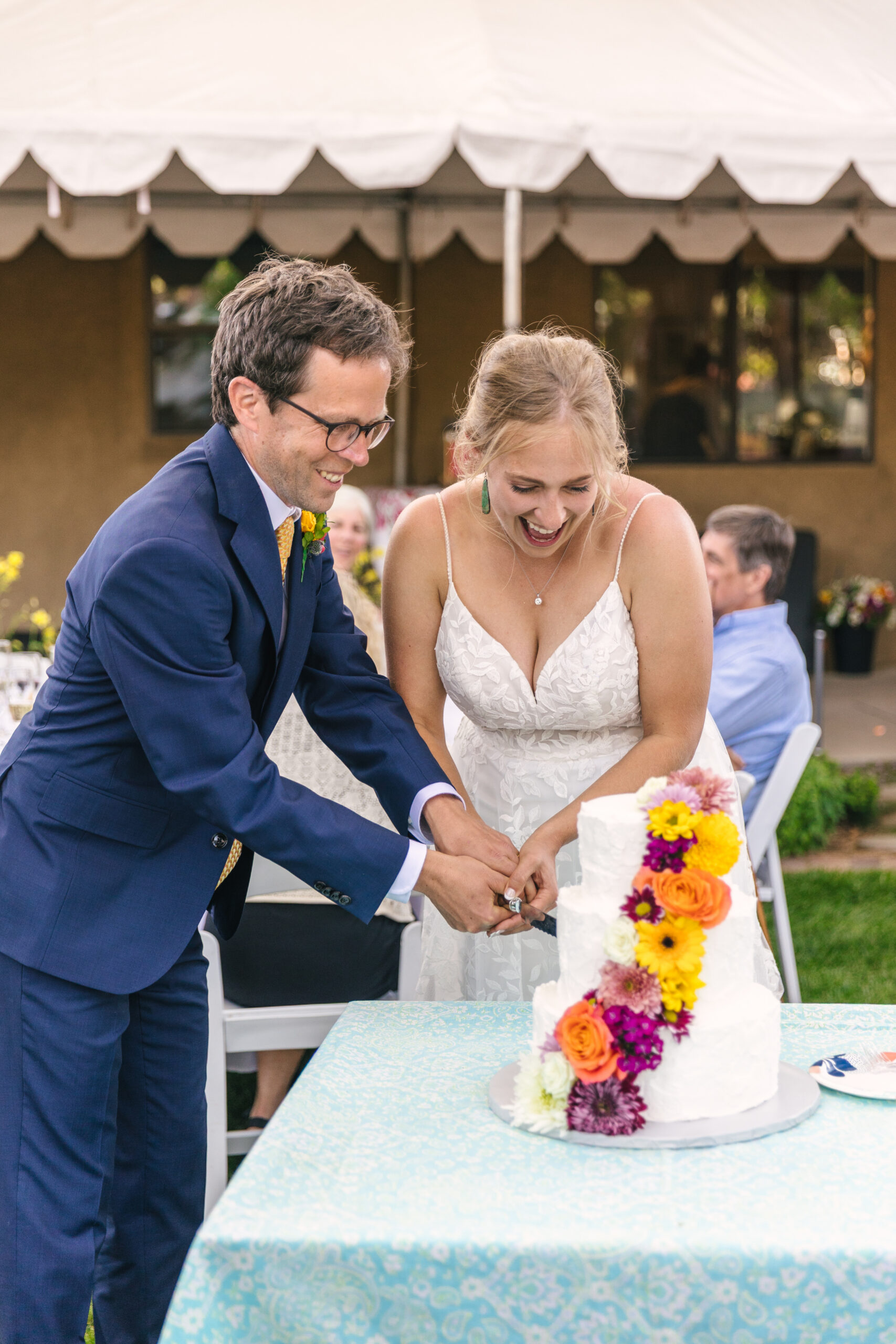 bride and groom cutting the cake at vibrant backyard wedding