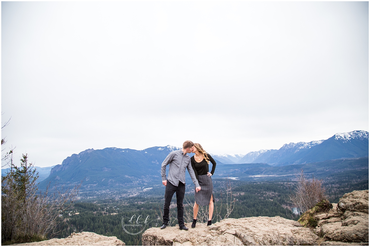 engaged couple kissing in front of vast Cascade Mountain landscape