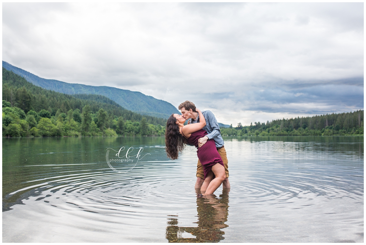 guy dipping his fiance back for a kiss in the water at Rattlesnake Lake