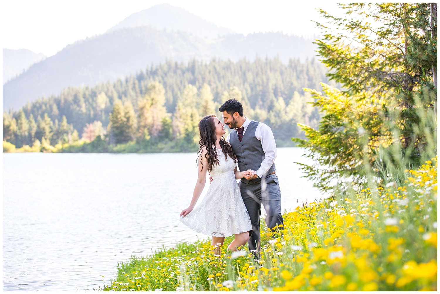 bride holding her dress and her fiance's hand in field of wildflowers at Gold Creek Pond