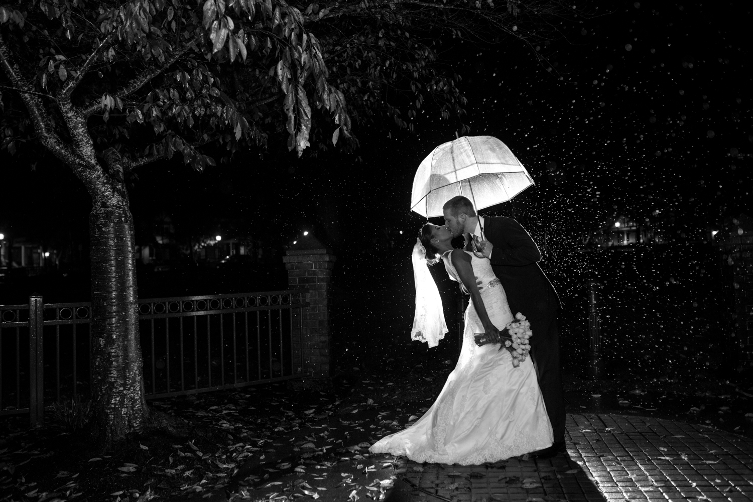 How to deal with rain on your wedding day: rainy night shot of bride and groom with umbrella.