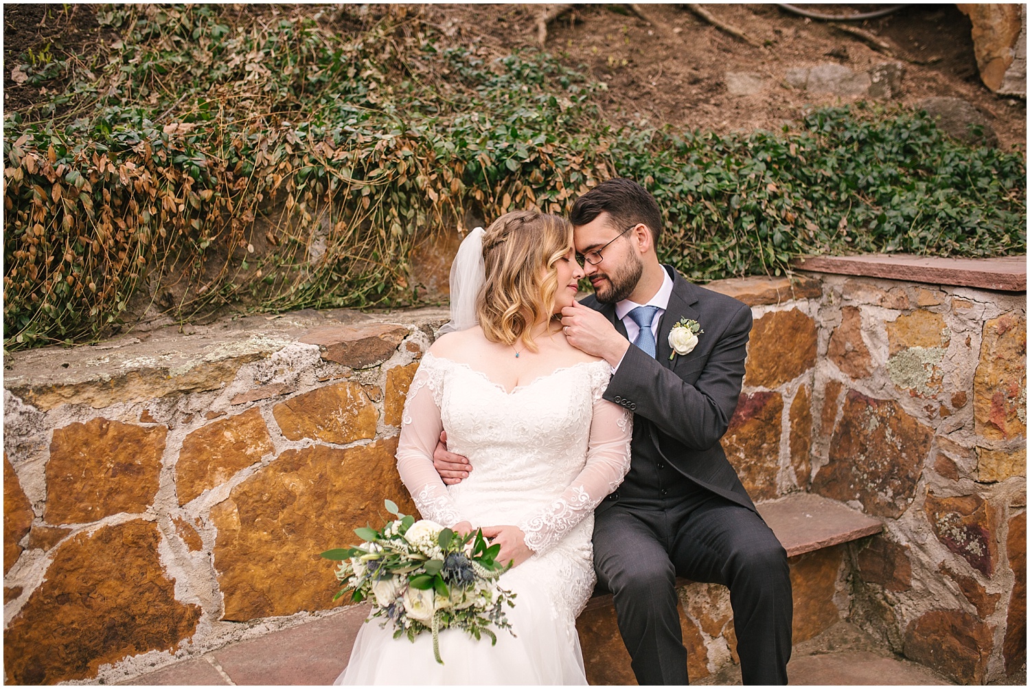 Bride and groom cuddling on a stone bench at Wedgewood Weddings Boulder Creek