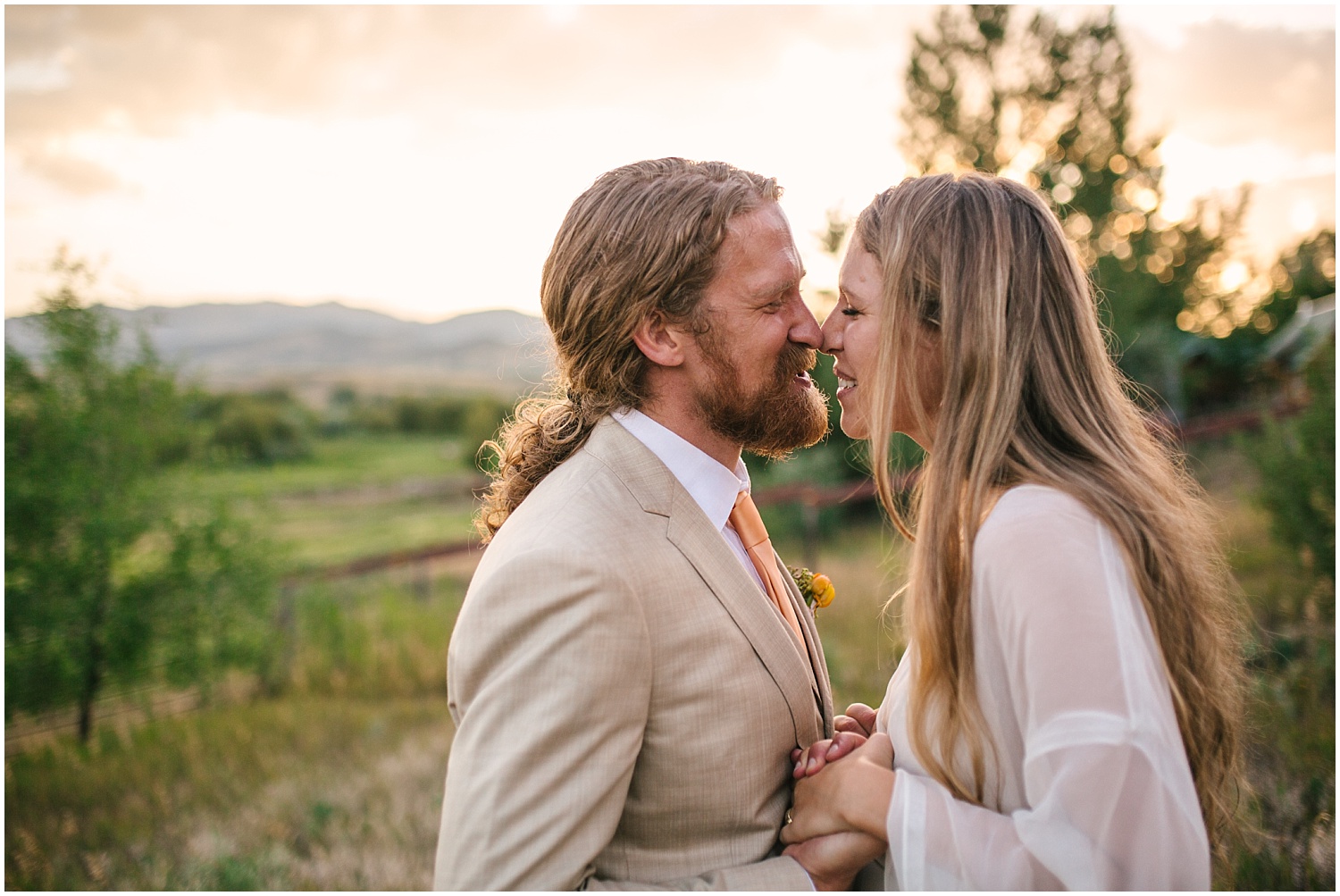 Bride and groom kissing in the mountains at sunset at Lone Hawk Farm wedding in Longmont Colorado