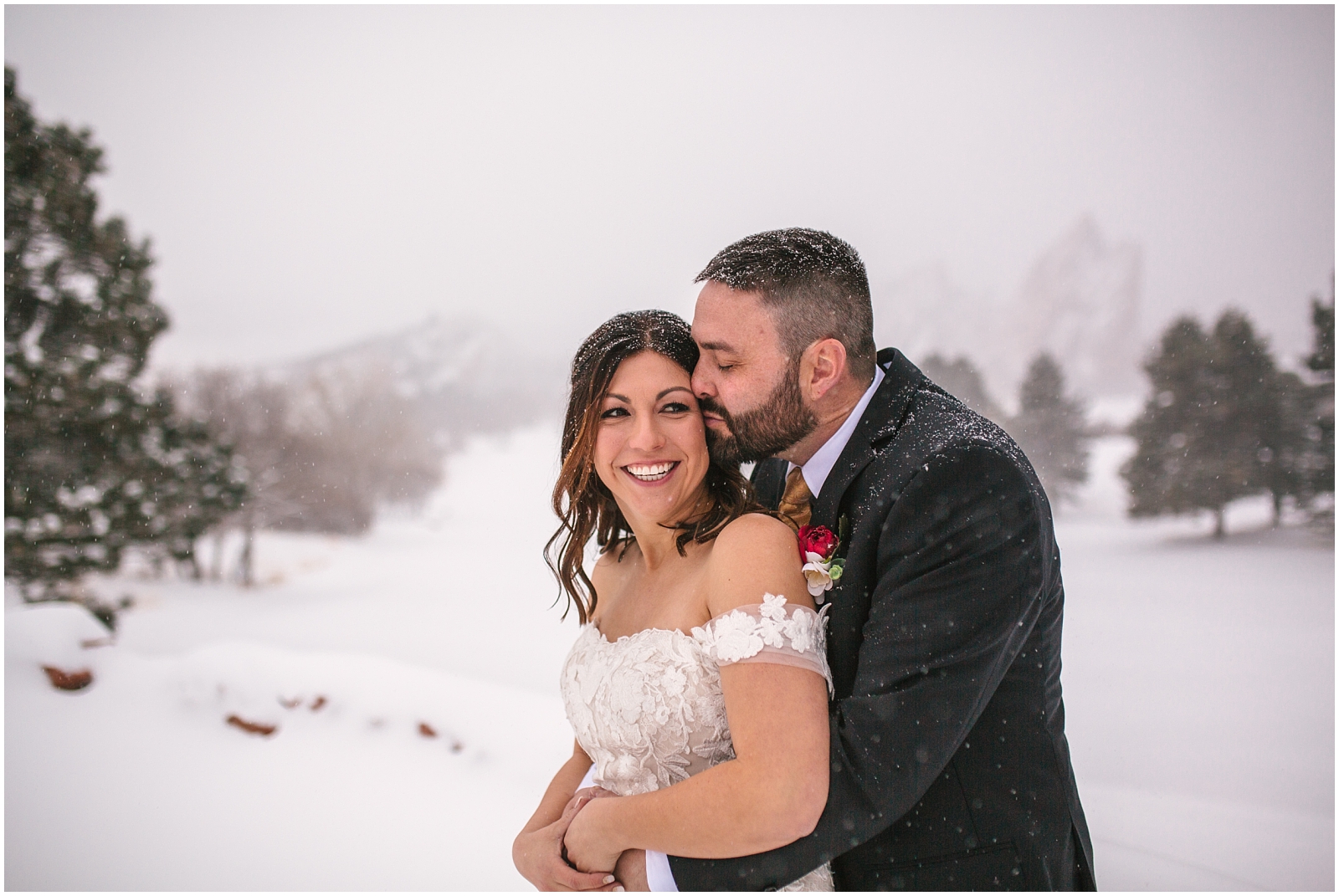 Bride and groom cuddling in the snow storm for their winter wedding at Arrowhead Golf Club