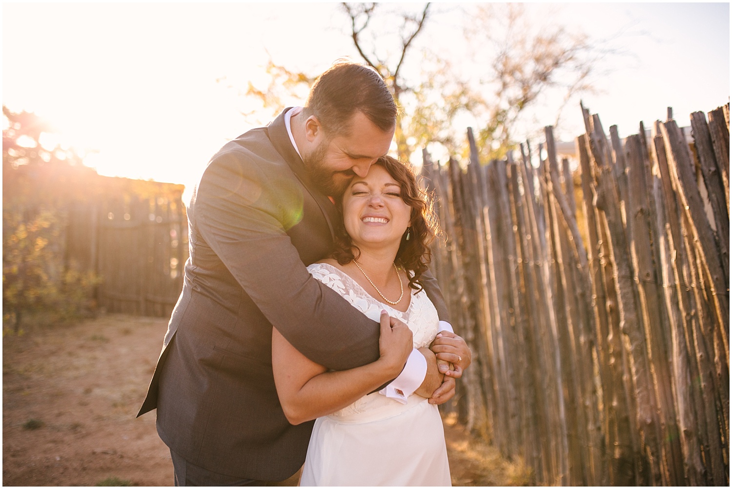 groom hugs his bride in the golden light at backyard wedding in Santa Fe