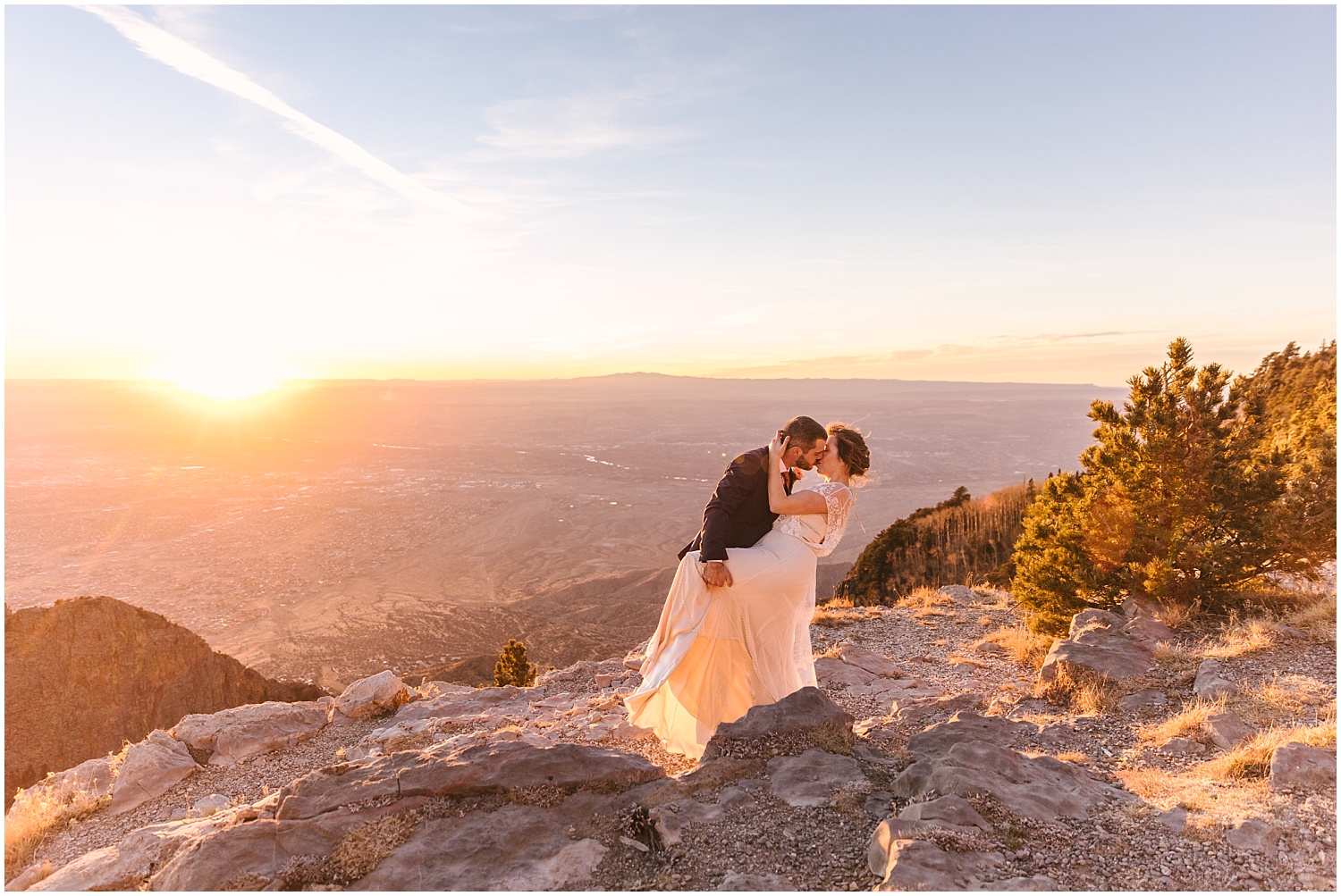 Groom dips bride for a kiss at sunset on Sandia Crest