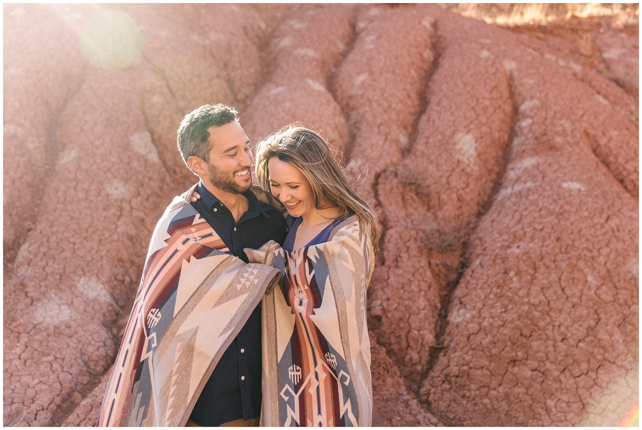 couple cuddling under Pendleton blanket for desert engagement photos in Abiquiu New Mexico