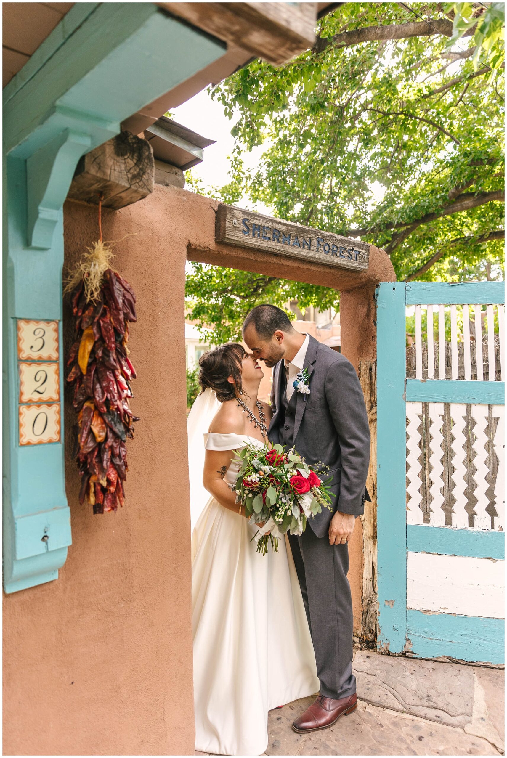Bride and groom kissing at the iconic turquoise gate at Casas de Suenos wedding venue in Old Town Albuquerque